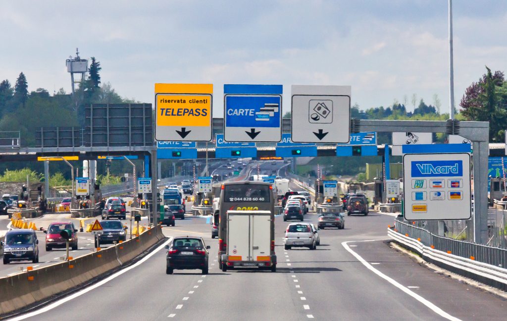 Casello autostradale italiano con corsie Telepass e traffico in ingresso