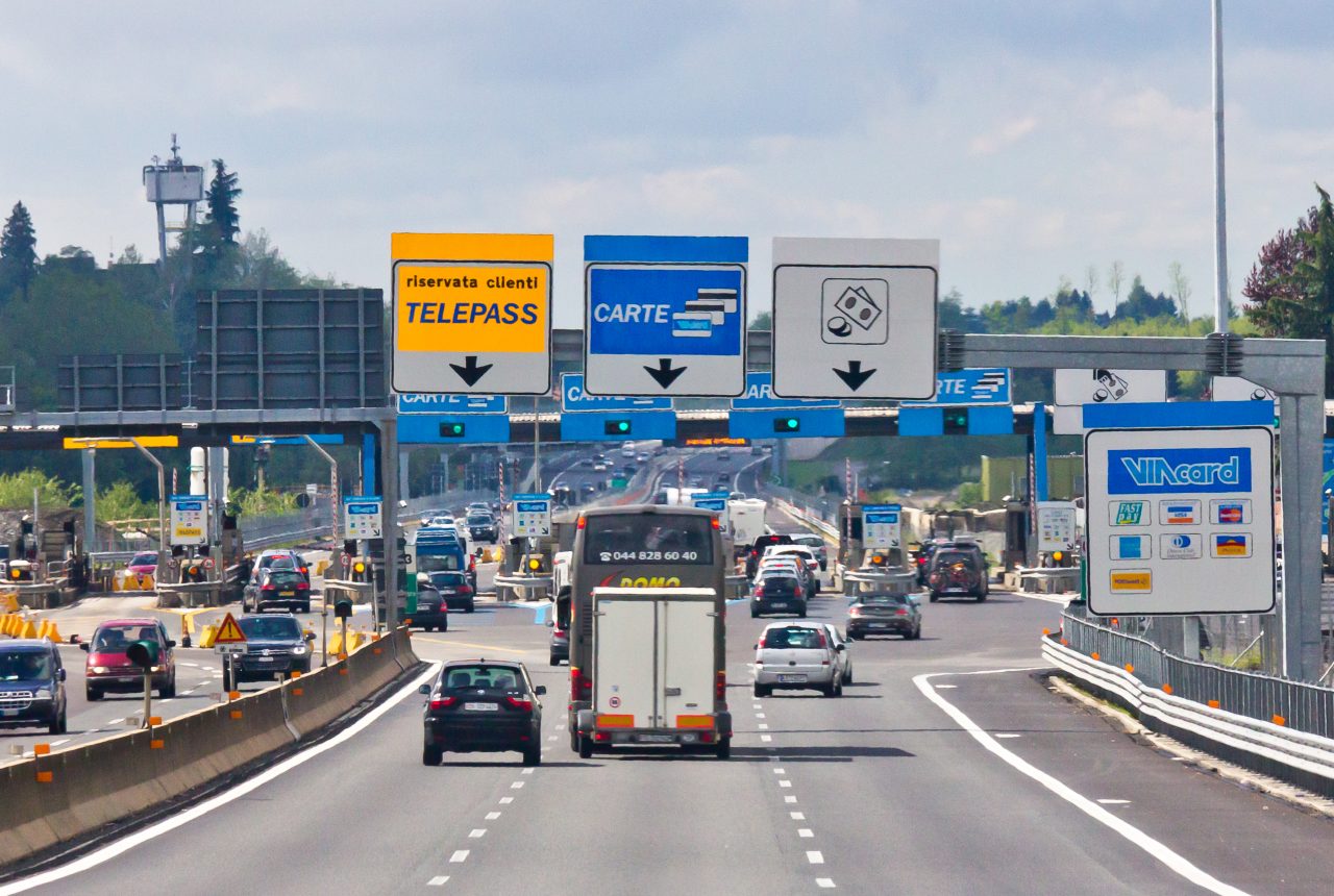 Casello autostradale italiano con corsie Telepass e traffico in ingresso